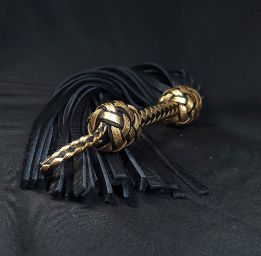 A handmade black and gold bison leather flogger