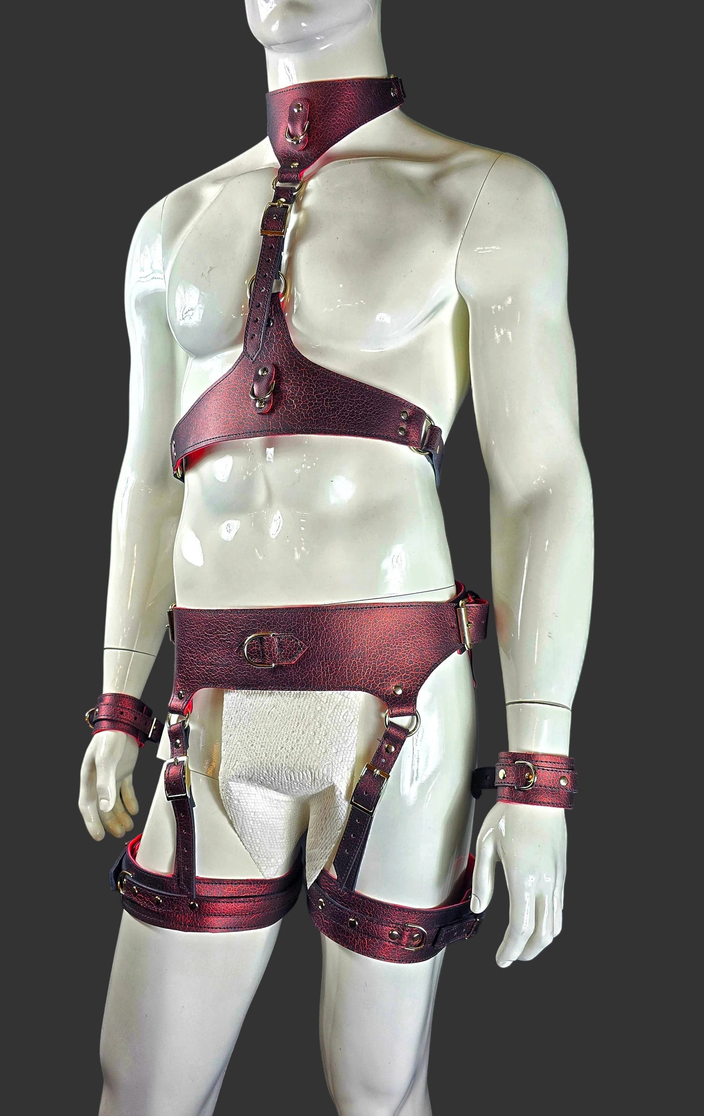 Mannequin wearing a red leather harness against a black background